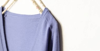 mavi yün kazak beyaz arka plan üzerinde giysi askısı asılı