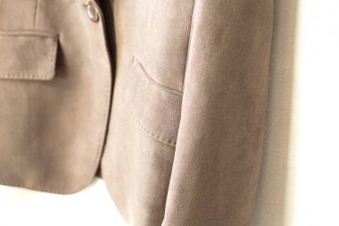 beyaz arka plan üzerinde giysi askısı asılı kahverengi ceket.