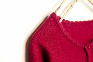 beyaz arka plan üzerinde giysi askısı asılı kırmızı bir hırka.