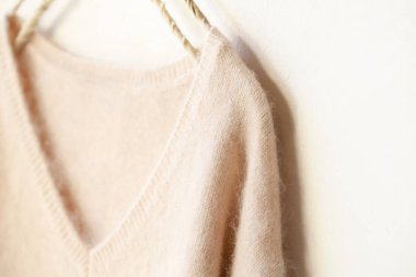 beyaz arka plan üzerinde giysi askısı asılı açık pembe kazak.