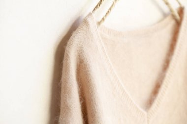 beyaz arka plan üzerinde giysi askısı asılı açık pembe kazak.