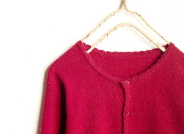 beyaz arka plan üzerinde giysi askısı asılı kırmızı bir hırka.