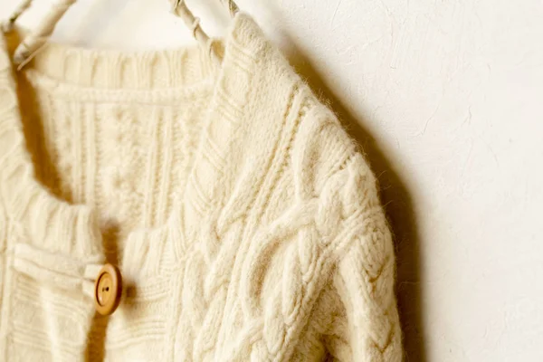 Gruby sweter z dzianiny w białym wiszącym na wieszaku na ubrania na białym tle. — Zdjęcie stockowe
