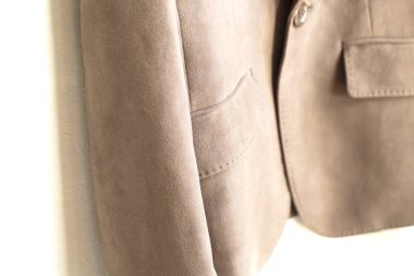 beyaz arka plan üzerinde giysi askısı asılı kahverengi ceket.