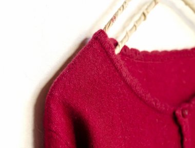 beyaz arka plan üzerinde giysi askısı asılı kırmızı bir hırka.