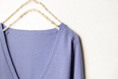 mavi yün kazak beyaz arka plan üzerinde giysi askısı asılı