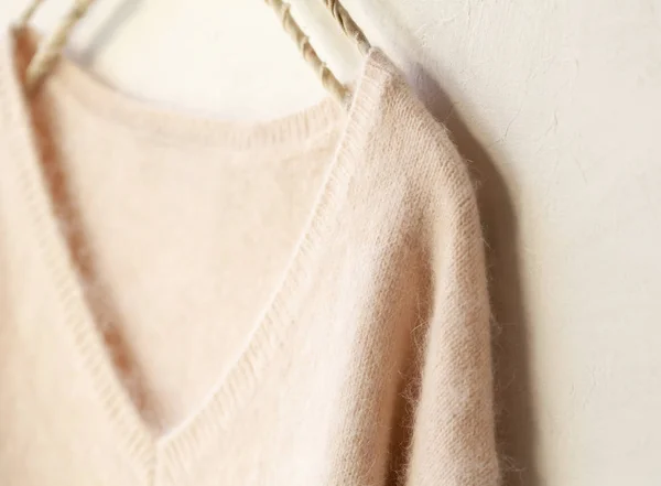 Jasnoróżowy sweter wiszący na wieszaku na białym tle. — Zdjęcie stockowe