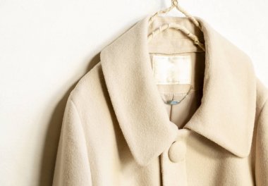 bej yün ceket beyaz arka plan üzerinde giysi askısı asılı