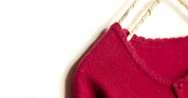 beyaz arka plan üzerinde giysi askısı asılı kırmızı bir hırka.