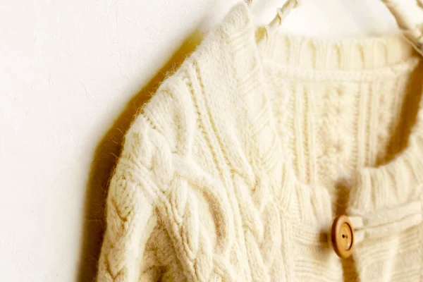 Gruby sweter z dzianiny w białym wiszącym na wieszaku na ubrania na białym tle. — Zdjęcie stockowe