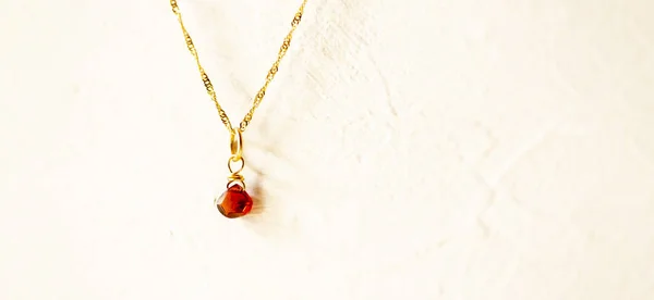 Zlatý náhrdelník s kamenem Kaštanově hnědého na bílém pozadí. — Stock fotografie