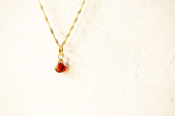 Golden necklace with the stone of the chestnut brown on white background. — Stock Photo, Image