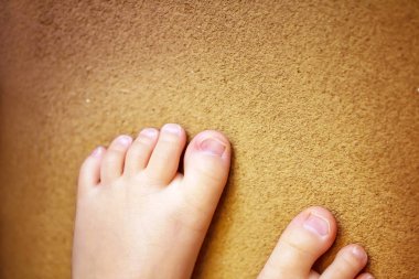 Çocukların çıplak ayakları. Kahverengi arka planda çocuk çıplak ayakları.