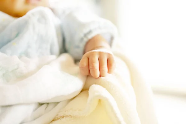 Bebê recém-nascido em um cobertor branco e azul claro - pequena mão do bebê . — Fotografia de Stock