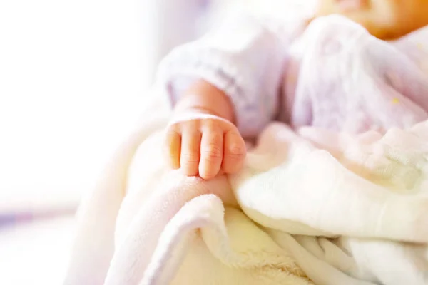 Bebê recém-nascido em um cobertor branco e azul claro - pequena mão do bebê . — Fotografia de Stock