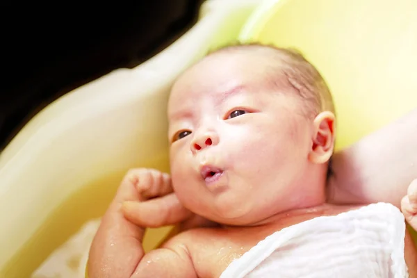 Niedliche Neugeborene nehmen ein Bad in der Babywanne. Das Baby ist entspannt. — Stockfoto