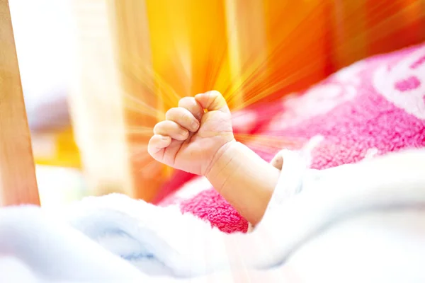 一个精力充沛的新生儿的手与浅蓝色和粉红色的毯子和婴儿床. — 图库照片