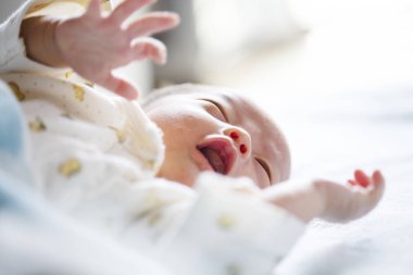 Sevimli yeni doğmuş bebek yatakta yatıyor, ağlıyor. Yakın çekim.