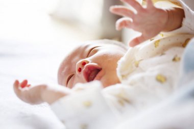 Sevimli yeni doğmuş bebek yatakta yatıyor, ağlıyor. Yakın çekim.