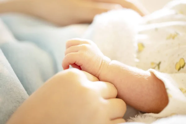 Newborn baby hand in mother's hands with soft light blue blanket. — Stock Photo, Image