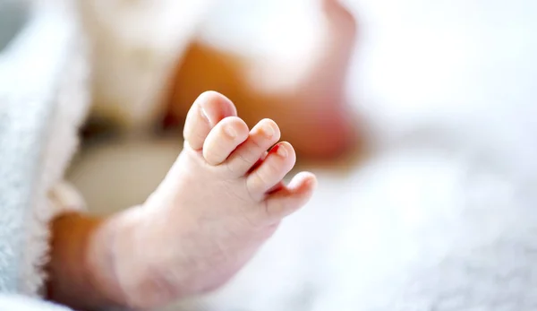 Neugeborenes Baby auf einer weißen und hellblauen Decke - winzige Babyfüße. — Stockfoto