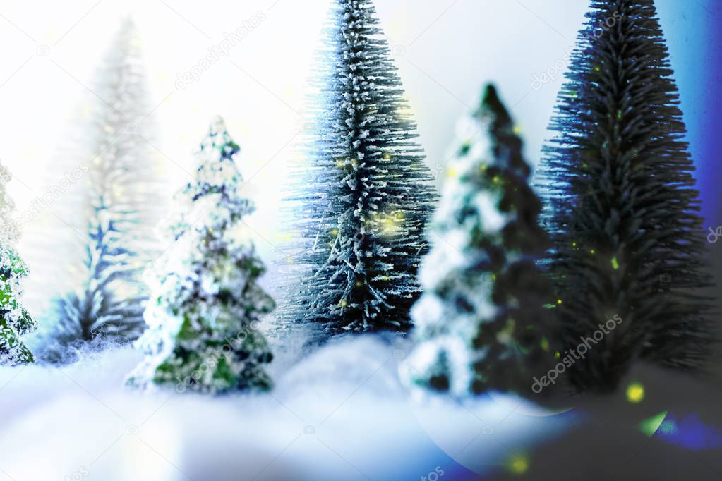 Mini snowy Christmas trees in the forest. Bokeh lights background