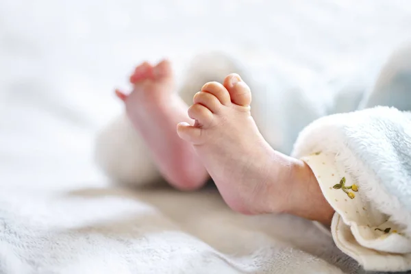 Bebê recém-nascido em um cobertor branco e azul claro - pequenos pés de bebê . — Fotografia de Stock