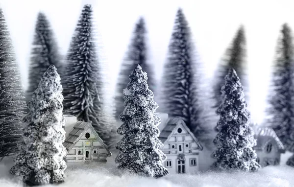 Mini snowy Christmas trees with houses in the forest. Bokeh lights background. — Stock Photo, Image