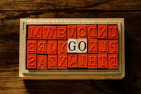 GO - isolated abstract in wood type stamps and against wooden background and copy space. — Stock Photo, Image