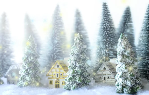 Mini árboles de Navidad nevados con casas en el bosque. Bokeh luces fondo . —  Fotos de Stock