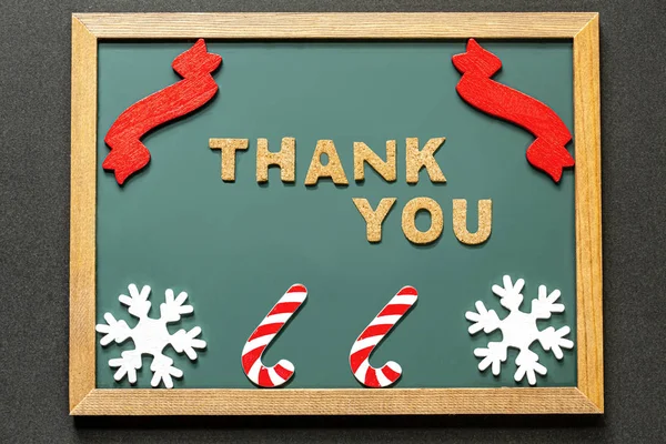 Set of THANK YOU of cork ,red ribbon, Candy Kane of the red white and two white snowy crystals isolated on green blackboard and black color background.