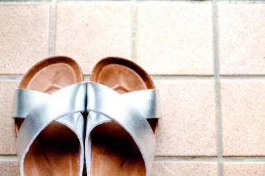 Bej kaplama arka planda gümüş bir çift terlik ve kopyalama alanı.