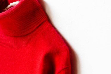 Kırmızı yün kazak asılıydı. Beyaz arka planda asılı duruyordu. Yaklaş..