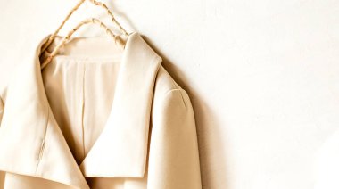 bej ya da beyaz ceket beyaz arka planda asılı. Yaklaş..