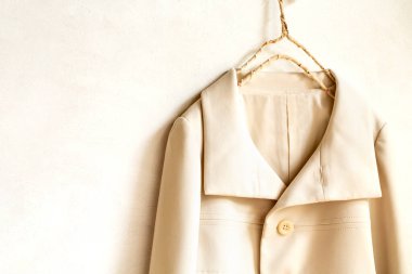 bej ya da beyaz ceket beyaz arka planda asılı. Yaklaş..