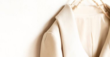 bej ya da beyaz ceket beyaz arka planda asılı. Yaklaş..