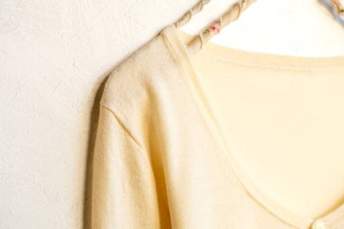 Beyaz elbiseli bir hırka beyaz arka planda asılı duruyor. Yaklaş..