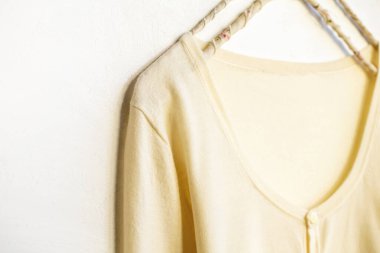 Beyaz elbiseli bir hırka beyaz arka planda asılı duruyor. Yaklaş..