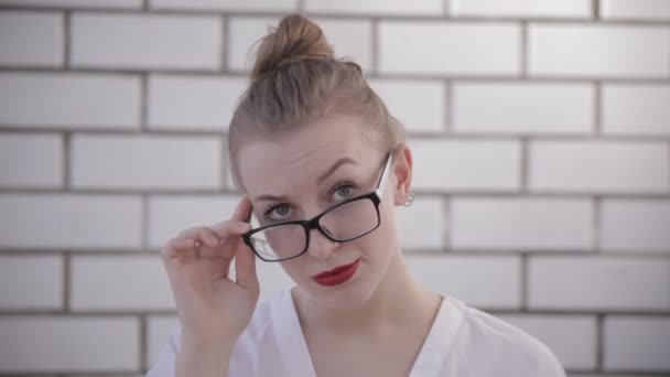 Mulher loira surpreso tocando óculos e dizer NÃO, empresária com batom vermelho no fundo branco — Vídeo de Stock