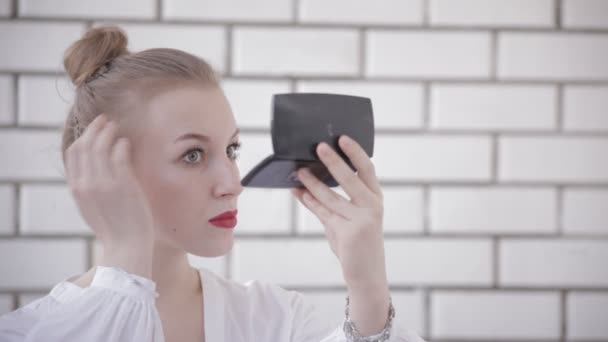Vonzó fiatal nő keres ellenőrzése sminkje kézzel tükörbe. érzéki fiatal női modell fekete háttér ellenében. — Stock videók