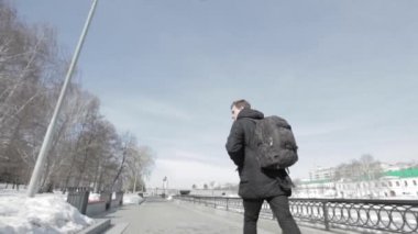 Sırt çantası ile genç adam şehirde boardwalk çöp plastik çöp atma yürür