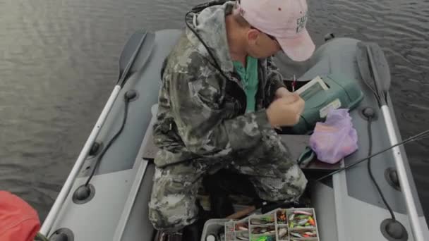 Homem preparando isca para a pesca. Pescador com uma vara de pesca no barco . — Vídeo de Stock