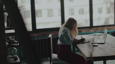 Masada oturan ve not defterinde yazılı genç kadın. Bağımsız çalışma.