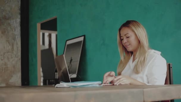 Ung kvinna sitter vid skrivbord, svara på samtal, medan arbetande i kontor — Stockvideo