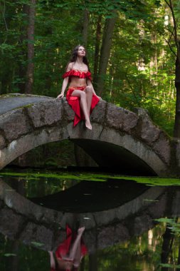 Ormandaki köprüde kırmızı elbiseli kadın