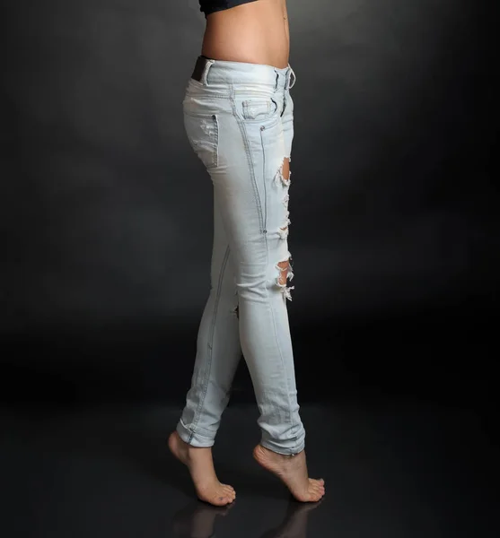 黑色背景撕裂牛仔裤的女性腿 — 图库照片