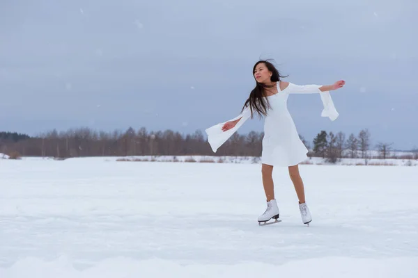 かなり若い女性冬冷凍公園屋外で白いドレスでスケート — ストック写真