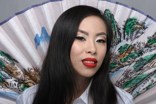 Portrait of beautiful young asian woman with fan on background