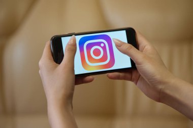 Instagram başlangıç sayfası ile cep telefonu tutan kadın elleri