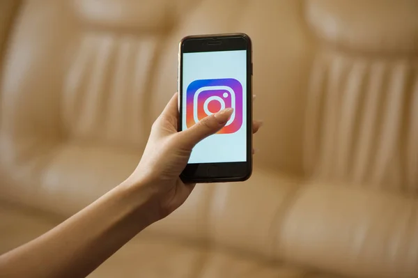 Женщина держит в руках мобильный телефон со стартовой страницей Instagram — стоковое фото